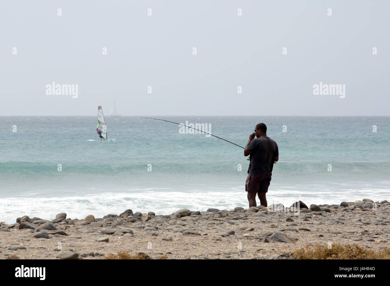 Man fishing off the beach Stock Photo