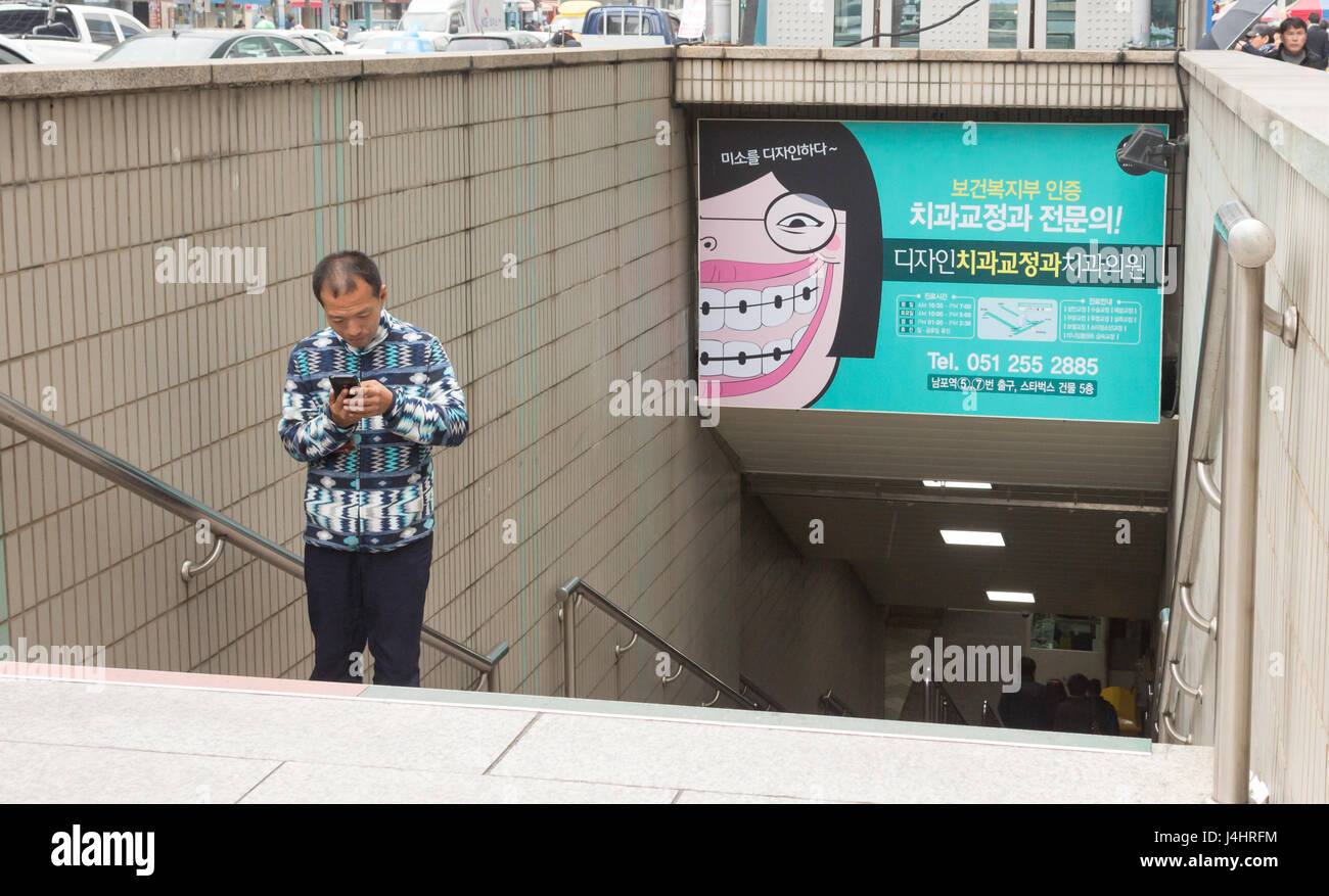 Busan, South Korea - March 27th, 2017: Korean man looking his mobile going out of the metro. Stock Photo