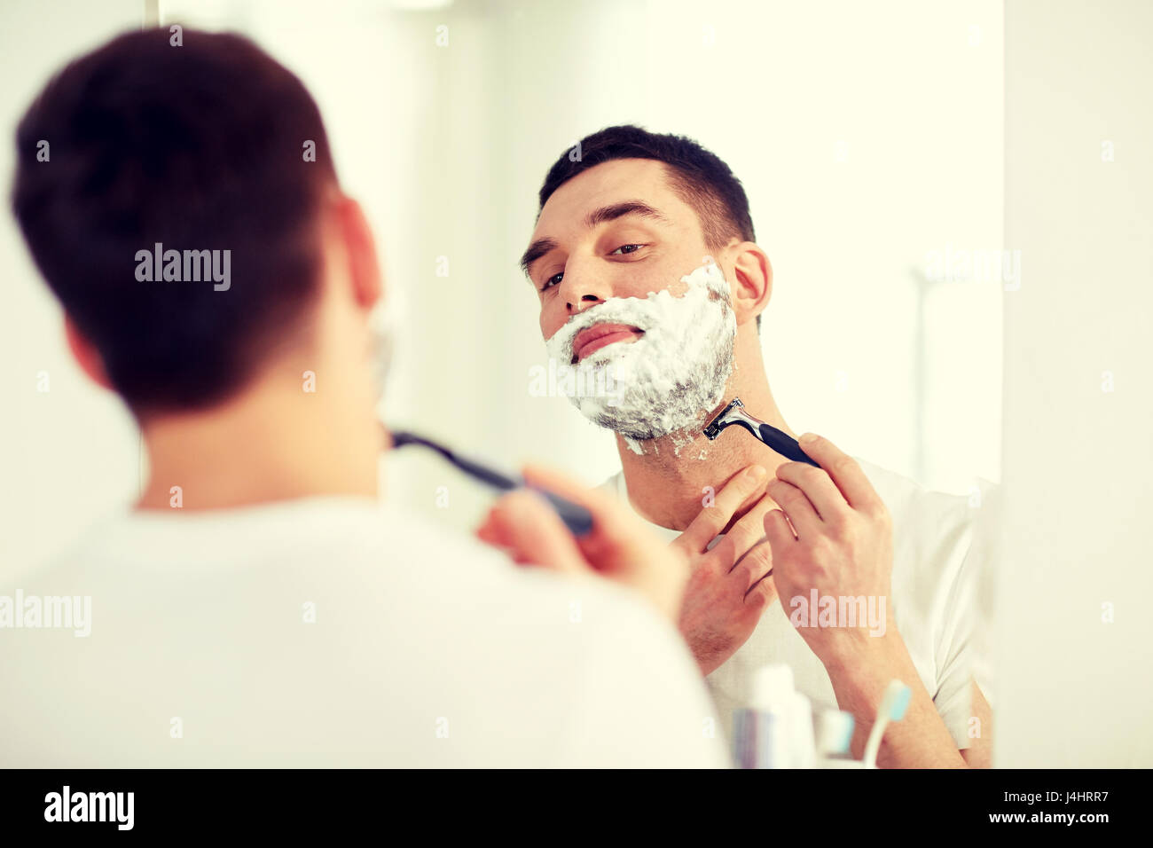 man shaving beard with razor blade at bathroom Stock Photo Alamy