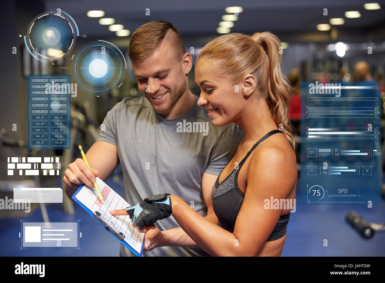 smiling woman with trainer and clipboard in gym Stock Photo