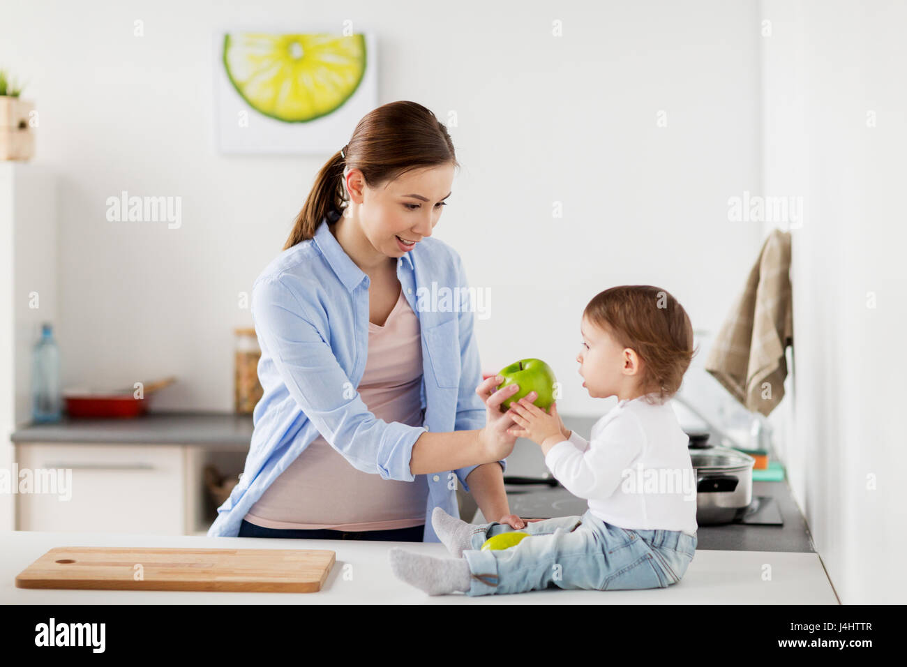mother giving green apple to baby at home kitchen Stock Photo Alamy