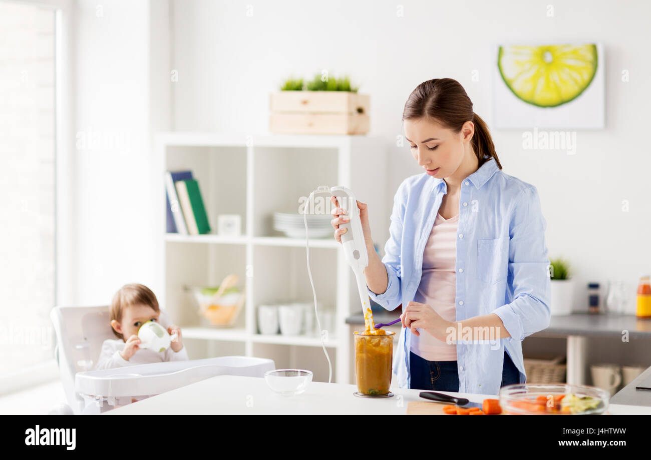 mother with blender cooking baby food at home Stock Photo