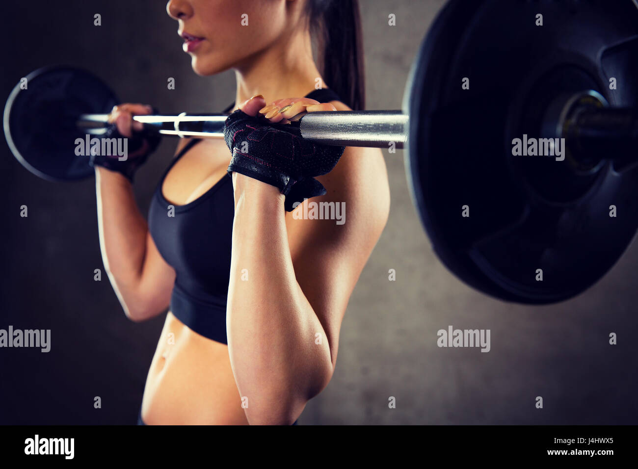 Tough young woman exercising with barbell. Determined female athlete  lifting heavy weights Stock Photo - Alamy