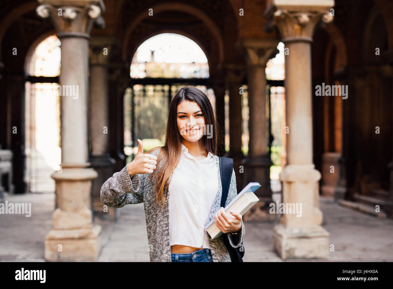 Portrait of a female student showing thumb up outdoors Stock Photo - Alamy