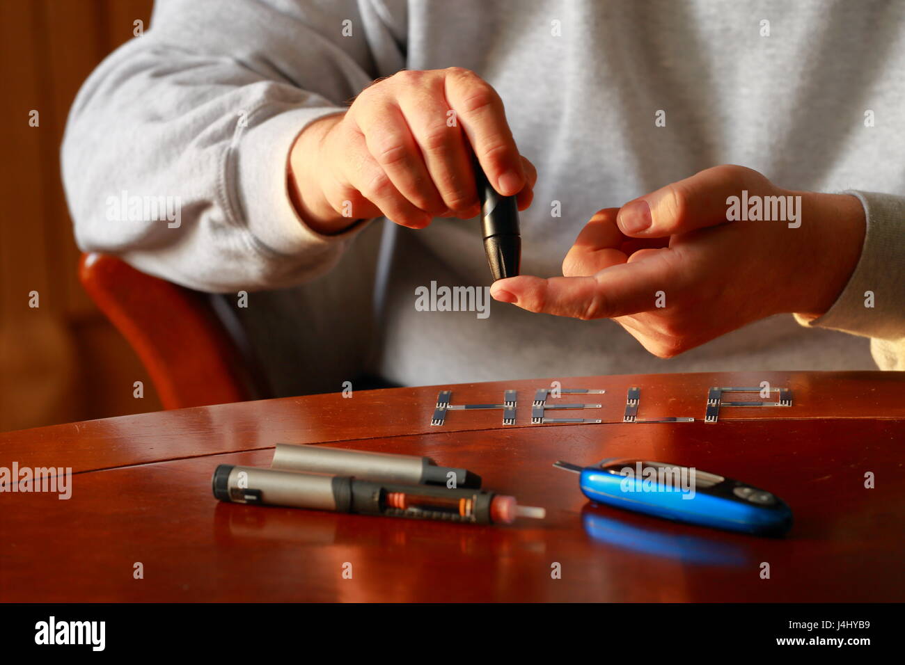 Diabetes. Blood glucose meter. Adult man measuring sugar level in blood at the table. Stock Photo