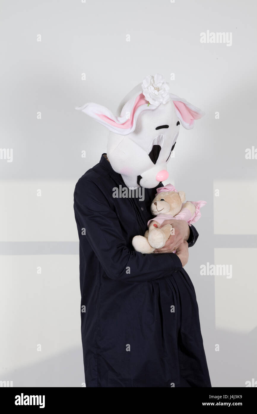 expectant mother rabbit rocking a teddy bear Stock Photo