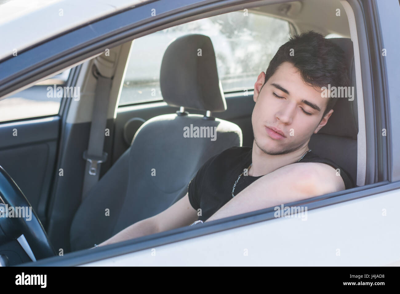 Young man sleeping at the wheel driving his car Stock Photo