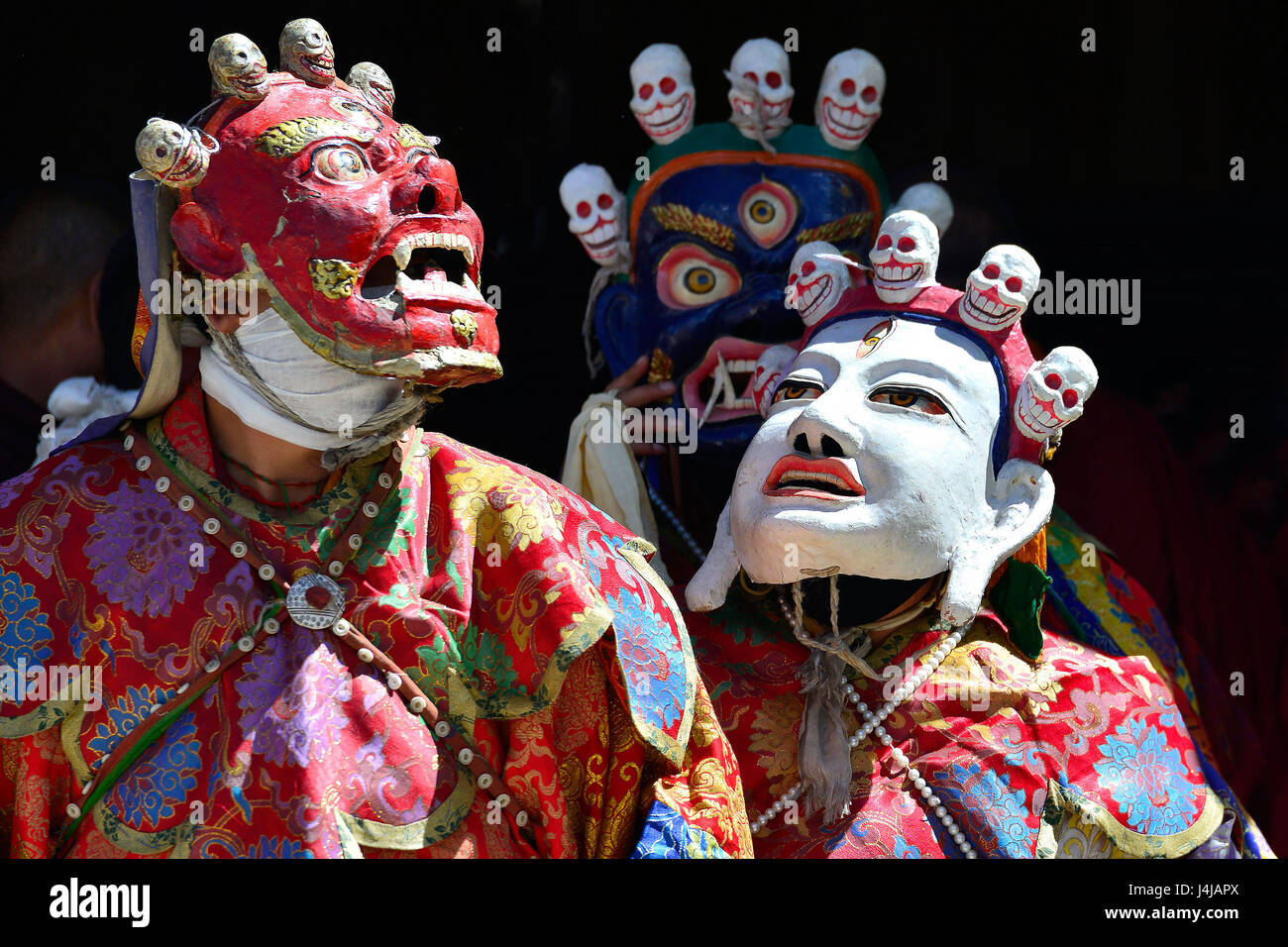 Buddhist mystery with the performance of Cham Dance in the Tibetan monastery in Zanskar: red, white and blue masks with skulls, bright red robes of mo Stock Photo