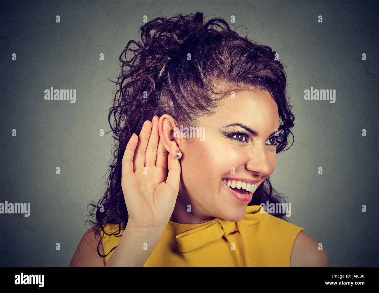 Woman with hand near ear listening carefully and smiling Stock Photo