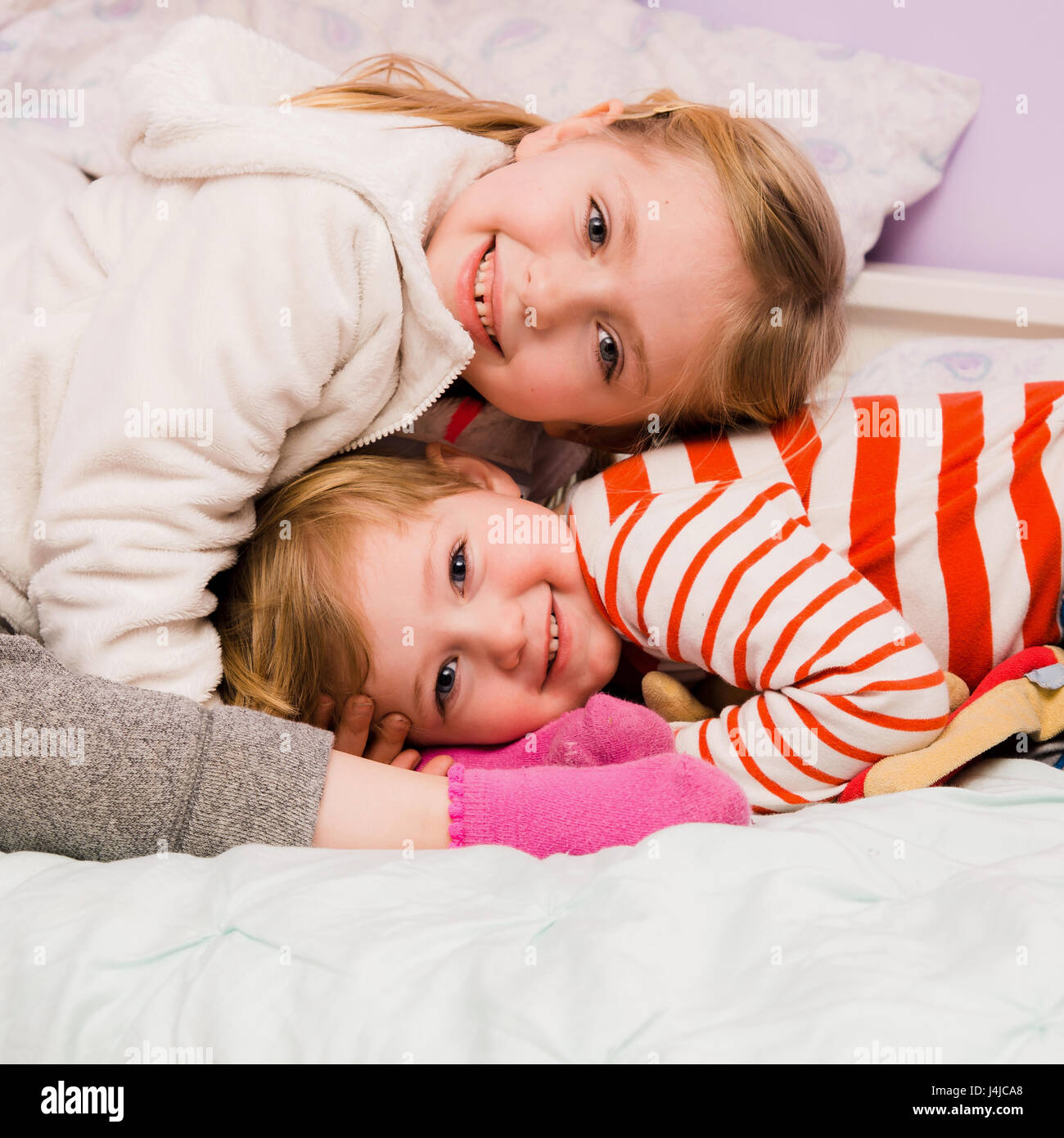 adorable brother and sister siblings hugging on bed together Stock Photo