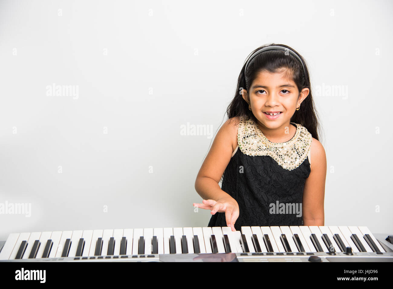 indian kids playing piano or keyboard, a musical instrument, isolated