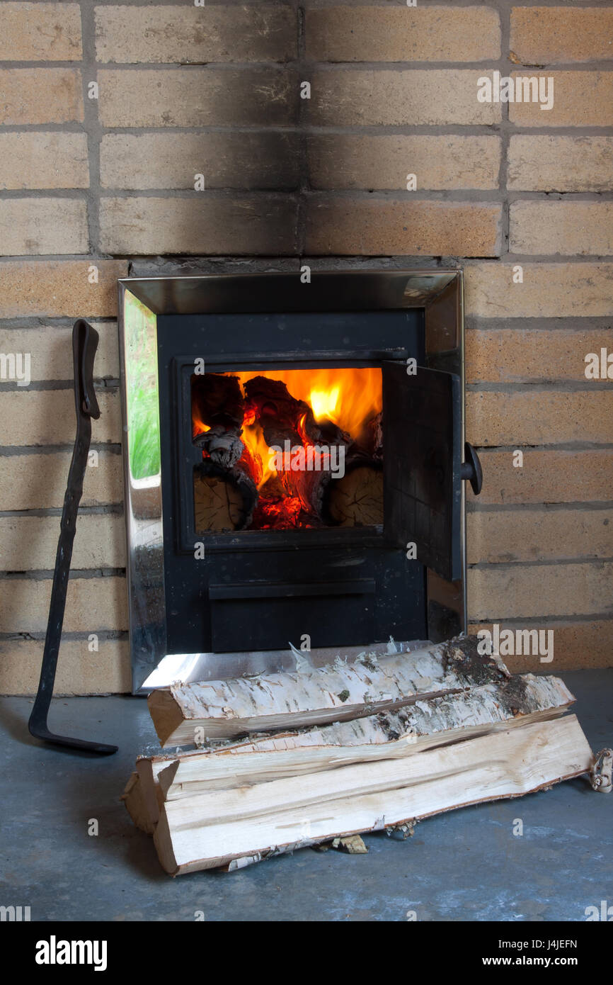 wood stove with firewood and poker Stock Photo