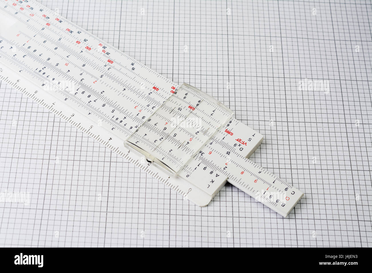 Old plastic slide ruler on millimeter paper Stock Photo