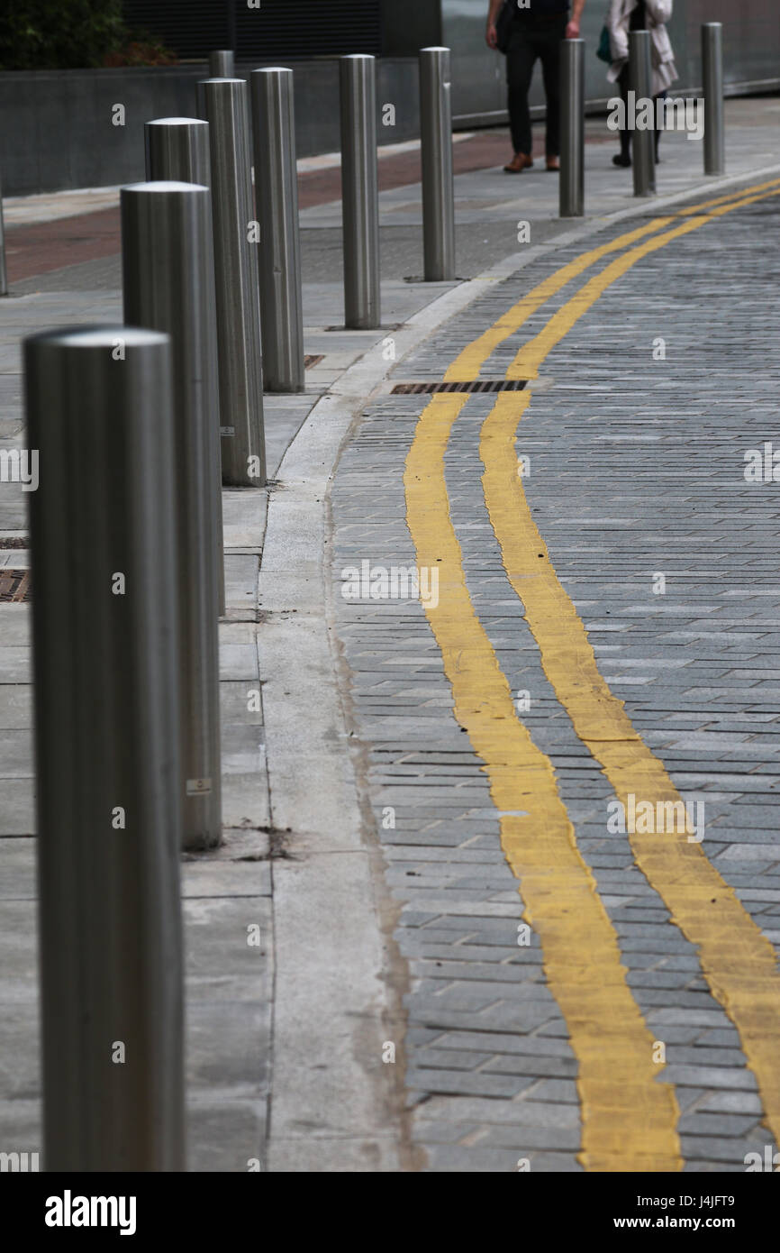 Double yellow lines on brick road with bollards Stock Photo
