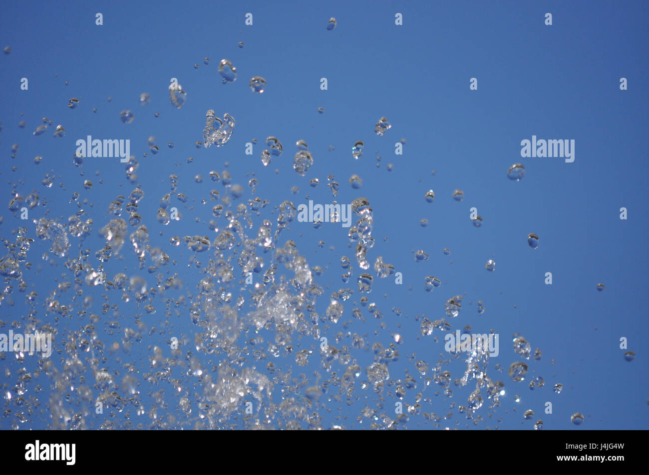 Water drops from fountain on the blue sky background - water in motion Stock Photo
