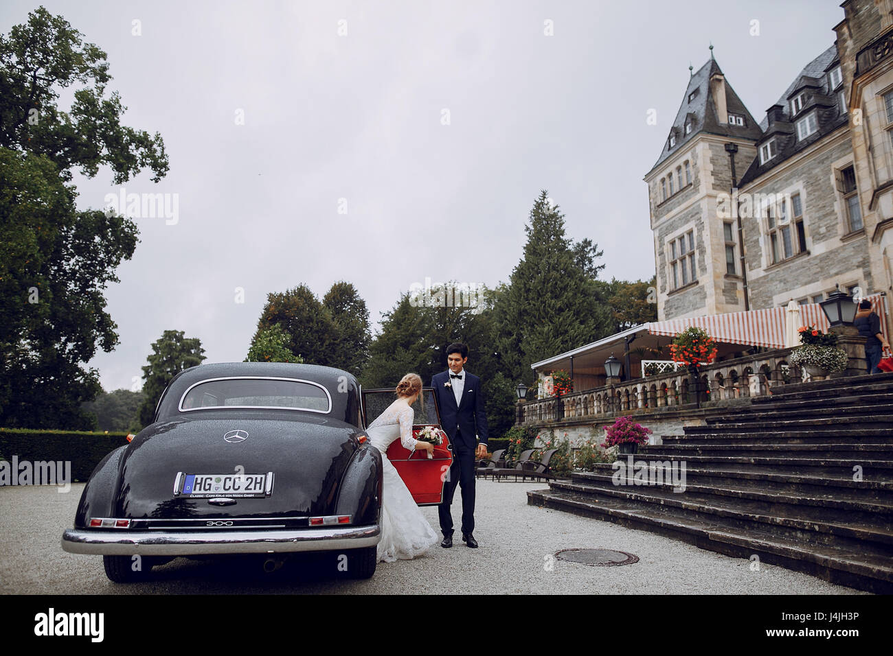 bride and groom standing near the castle and machinery Stock Photo - Alamy