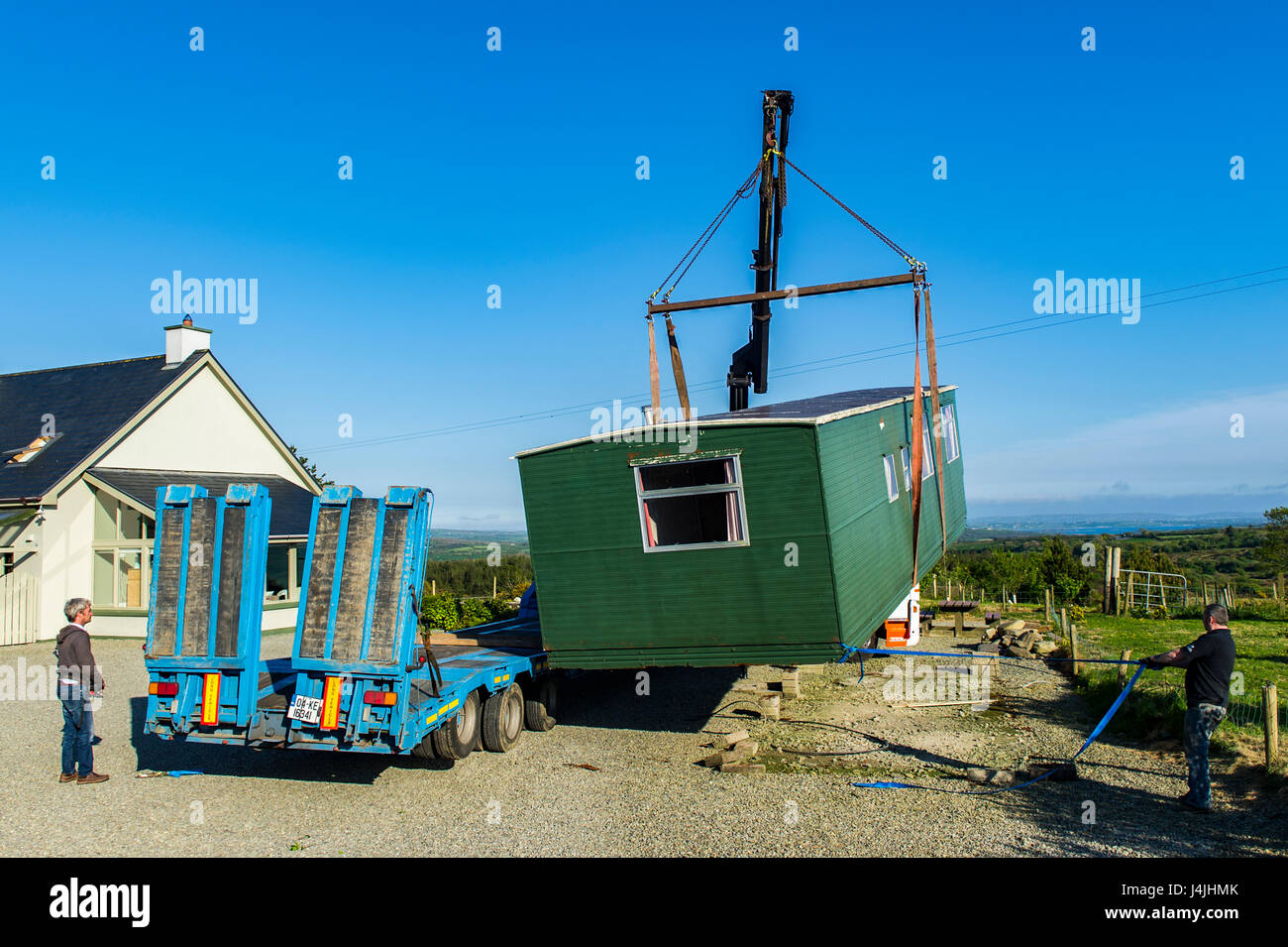 Old mobile home is lifted onto a low loader to be taken away for salvage/scrap/recycling mobile home removal with copy space. Stock Photo
