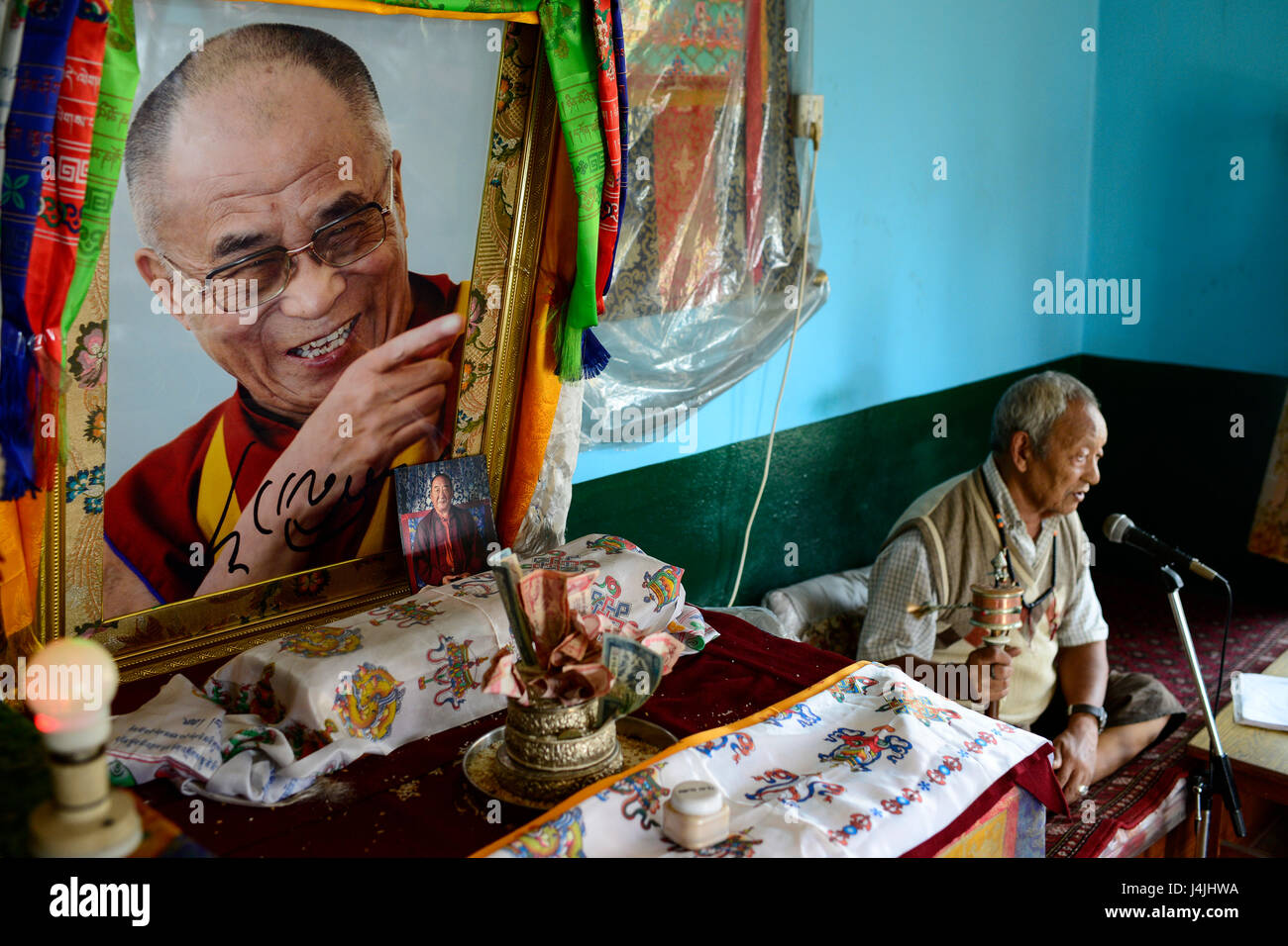 NEPAL Pokhara, tibetan refugee camp Prithvi, old tibetan freedom fighter during prayer time, image of HHDL Dalai Lama / tibetisches Fluechtlingslager Prithivi, alte Tibeter bei einem Gebet mit Gebetsmuehlen, Bildnis des Dalai Lama Stock Photo