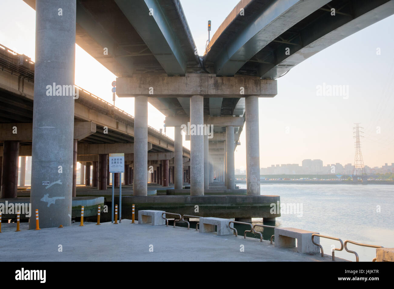 NEW TAPEI CITY, TAIWAN: Urban view under the Sun Yat-sen Freeway 1 over the Tamsui River. Sunbeams shine along the concrete pillars under the road. Stock Photo