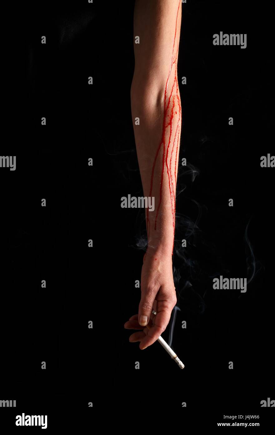 Bleeding arm with hand holding a cigarette, studio shot. Stock Photo