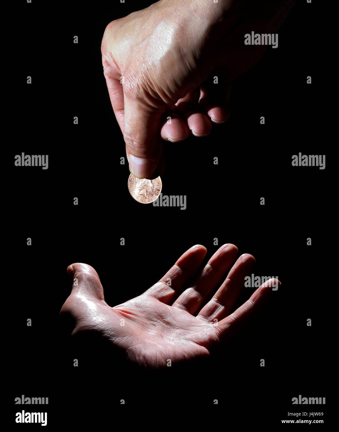 Person dropping coin on palm of hand, studio shot. Stock Photo