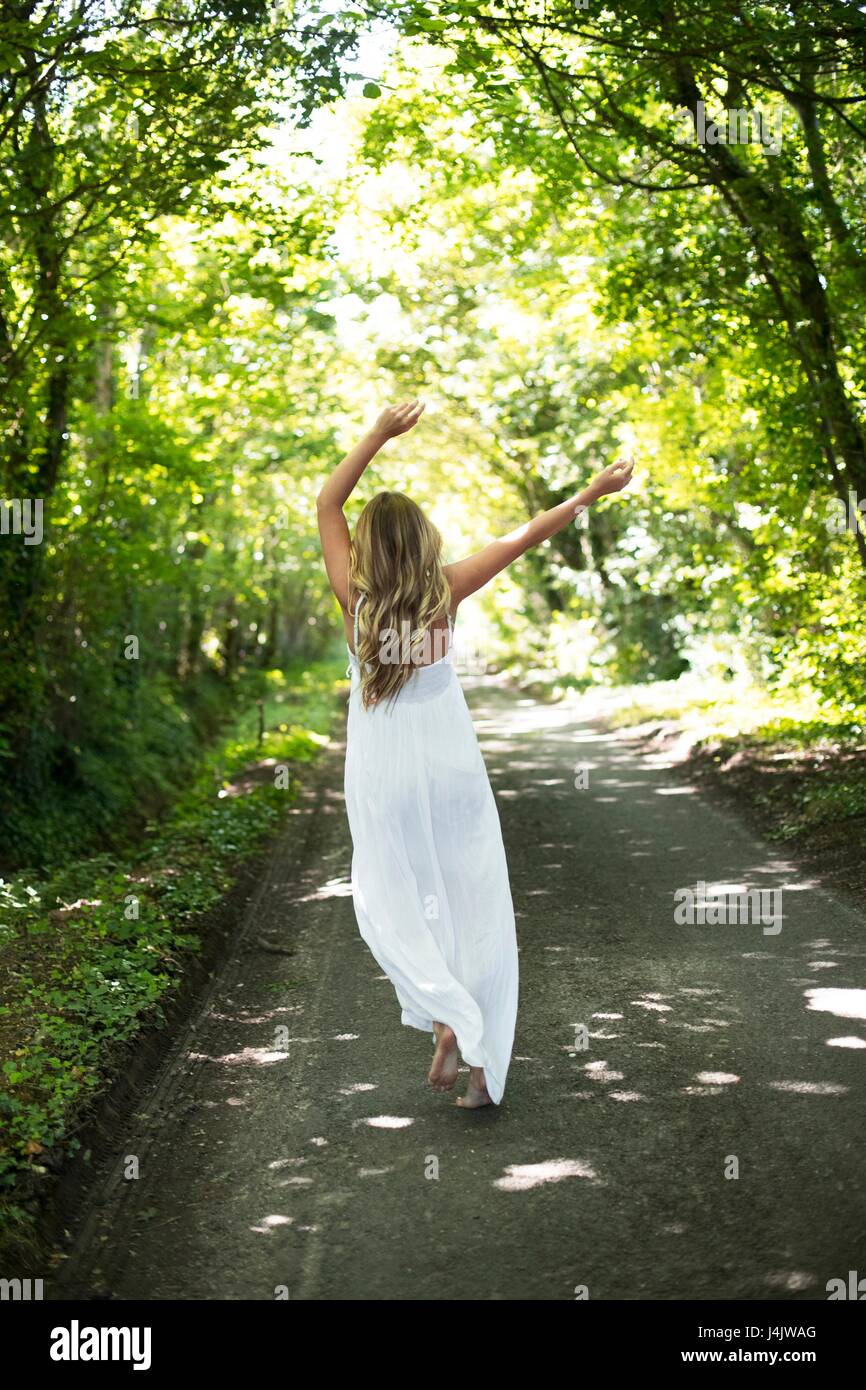 Young woman in long white dress on country lane Stock Photo - Alamy