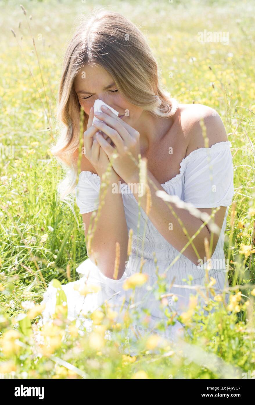Young woman blowing nose on tissue Stock Photo - Alamy