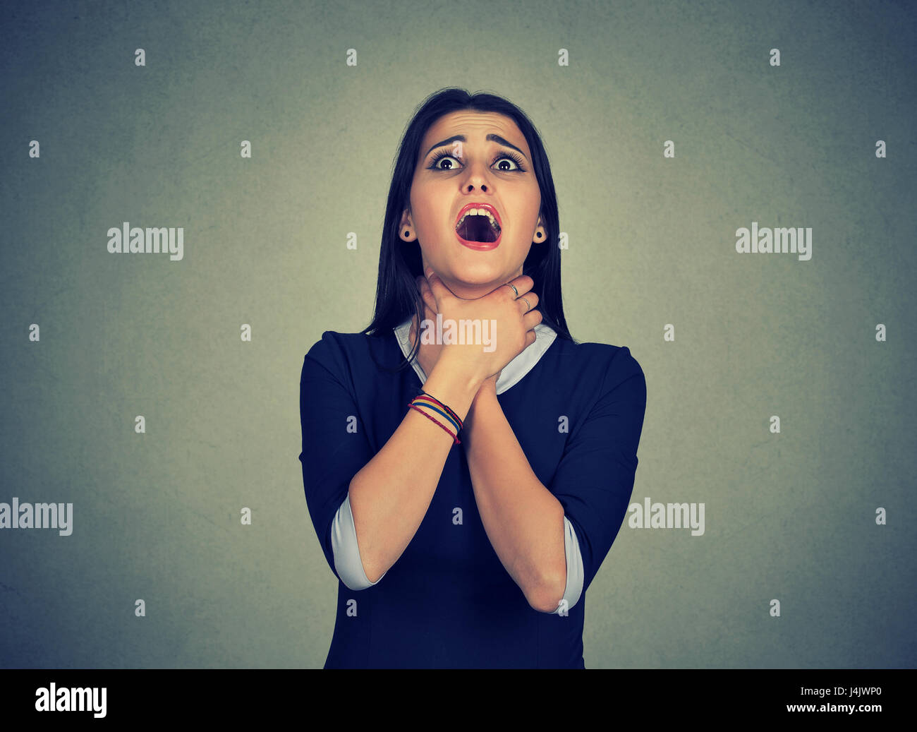 Young woman having asthma attack or choking can't breath suffering from respiration problems isolated on gray background Stock Photo