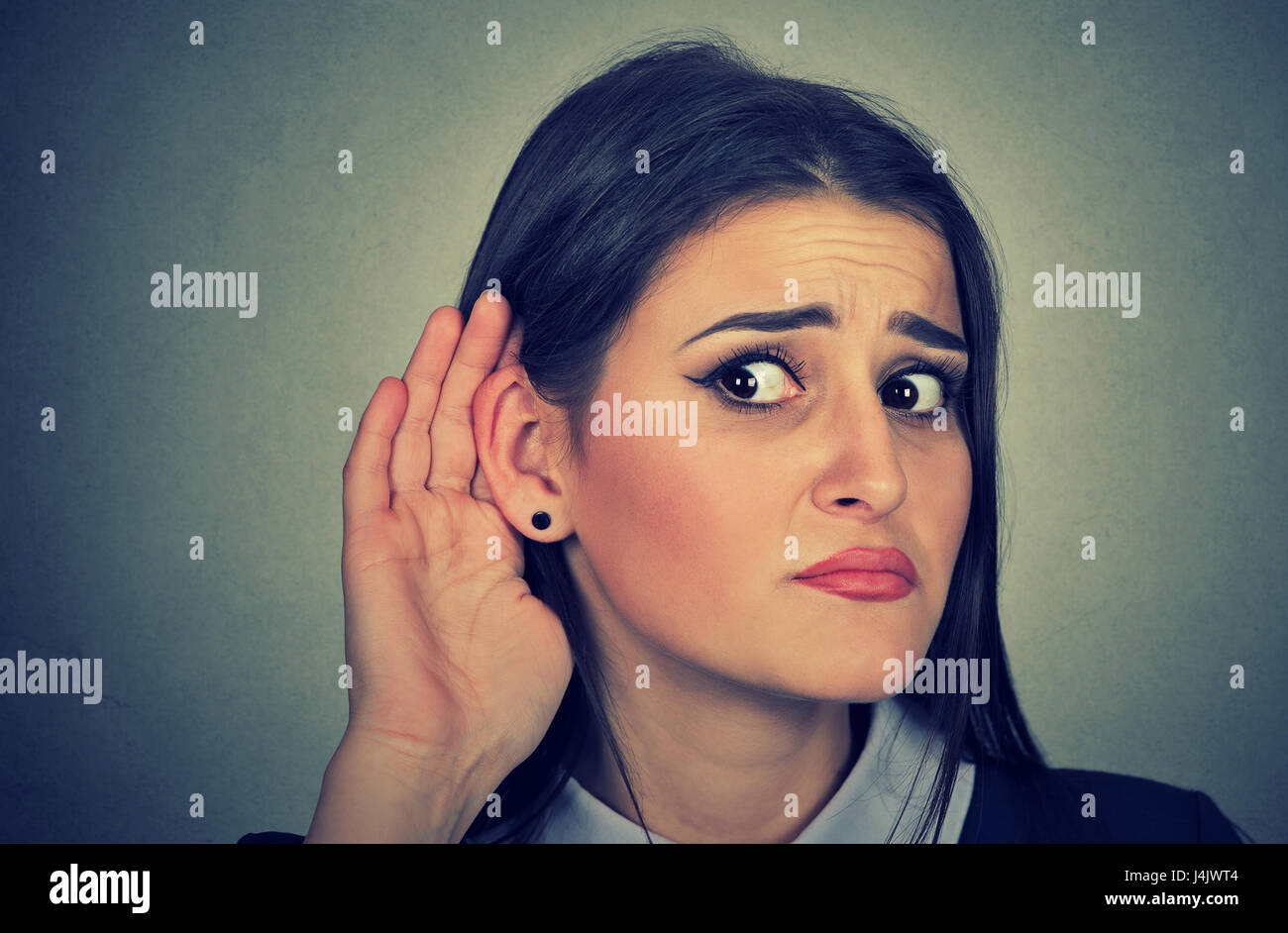 Woman with hand to ear gesture listening carefully Stock Photo