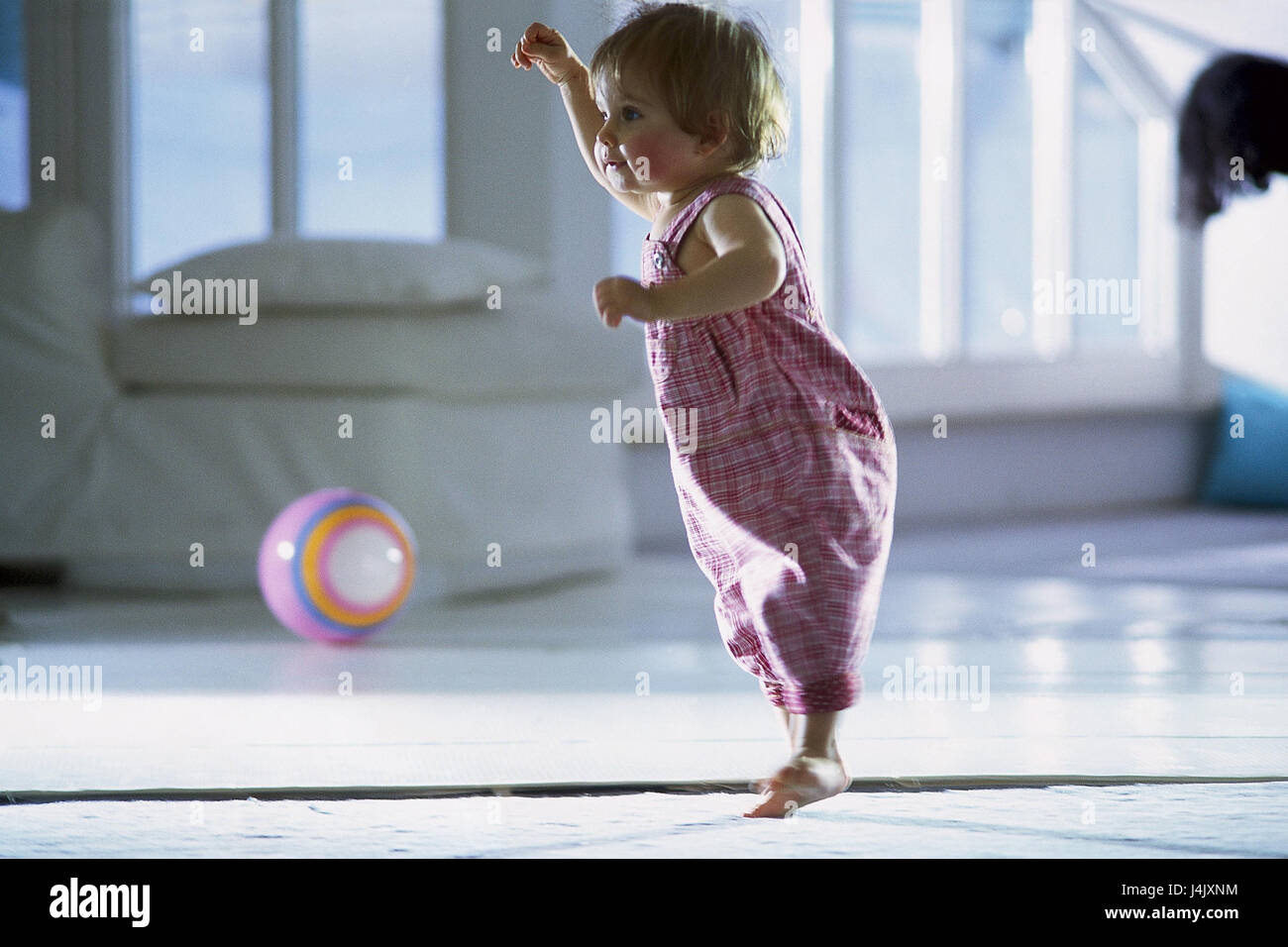 Infant, girl, jump, play ball, at home, child, childhood, barefoot, stand, to ball games, joy, please, whole body, at the side Stock Photo