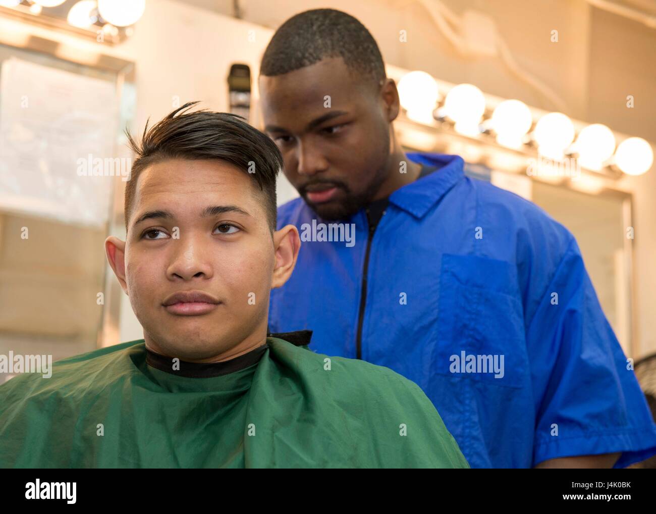 SAN DIEGO (Sept. 30, 2016) Petty Officer 3rd Class Breyon Holland gives Seaman Yuri Estrella a haircut in the ship’s enlisted barber shop onboard amphibious assault ship USS Boxer (LHD 4). Boxer returned to its homeport, San Diego, September 12, following a seven-month deployment to the 3rd, 5th, and 7th Fleet areas of operation. (U.S. Navy photo by Petty Officer 3rd Class Jesse Monford/Released) Stock Photo