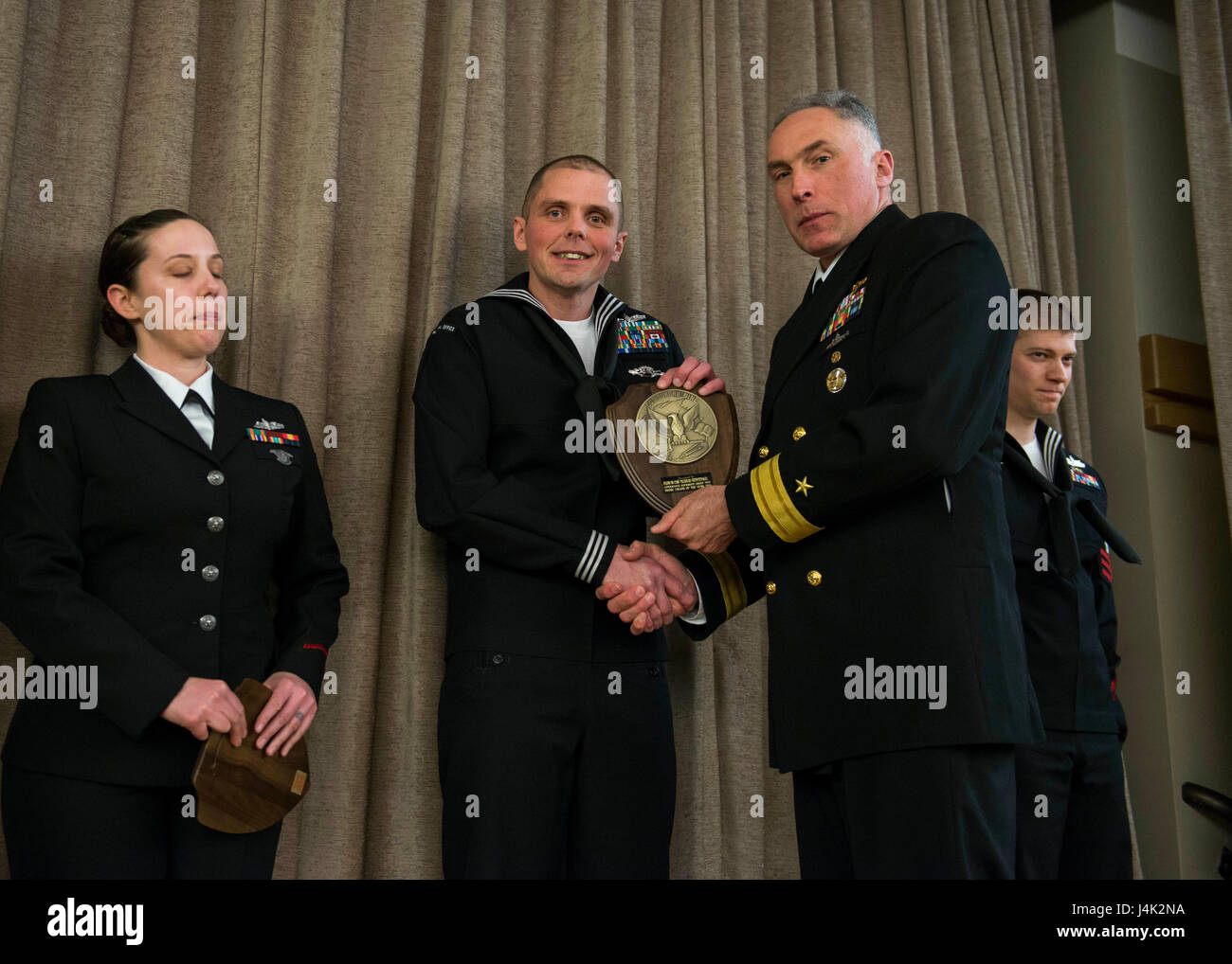 BANGOR, Wash. (Jan. 29, 2016) Rear Adm. John Tammen, commander, Submarine Group 9, congratulates Information Systems Technician 1st Class Nicholas Stenftenagel, from Jasper, Indiana, assigned to Priority Material Office (PMO) Bremerton, on becoming the 2016 Commander, Submarine Group Nine Shore Sailor of the Year. He will move on to participate in the Commander Submarine Force, U.S. Pacific Fleet (SUBPAC) Sailor of the Year competition, which will kick off next month in San Diego. (U.S. Navy photo by Mass Communication Specialist 1st Class Amanda R. Gray/Released) Stock Photo