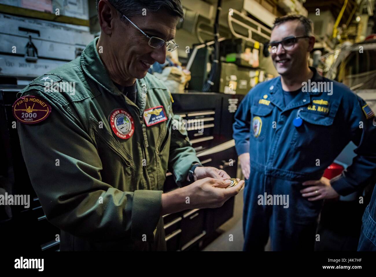 170503-N-TV230-281 PACIFIC OCEAN (May 3, 2017) Rear Adm. James Bynum, commander of Carrier Strike Group (CCSG) 9, right, receives challenge coins from Cmdr. Tim LaBenz, commanding officer of the guided-missile destroyer USS Sampson (DDG) 102, during a Group Sail training unit exercise (GRUSL) with the Theodore Roosevelt Carrier strike Group (TRCSG). GRUSL is the first step in the Theodore Roosevelt’s integrated training phase and aims to enhance mission-readiness and warfighting capabilities between the ships, airwing and the staffs of the TRCSG through simulated real-world scenarios. (U.S. Na Stock Photo
