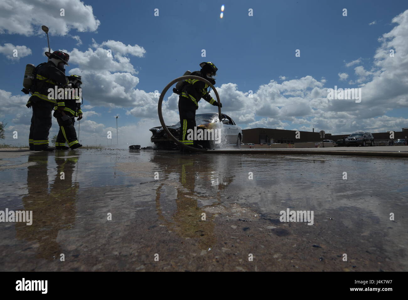 Members of the Tinker Fire and Emergency Services, 72nd Civil Engineer Squadron, work together to extinguish a vehicle fire May 4, 2017, Tinker Air Force Base, Oklahoma. William Green hoses the wheel-well of the car down while Capt. David Jones, left, and Aaron Simpson, background, stands-by as spotters. The privately-owned vehicle developed mechanical trouble and caught fire near the Oklahoma City Air Logistics Complexs' building 9001. (U.S. Air Force photo/Greg L. Davis) Stock Photo