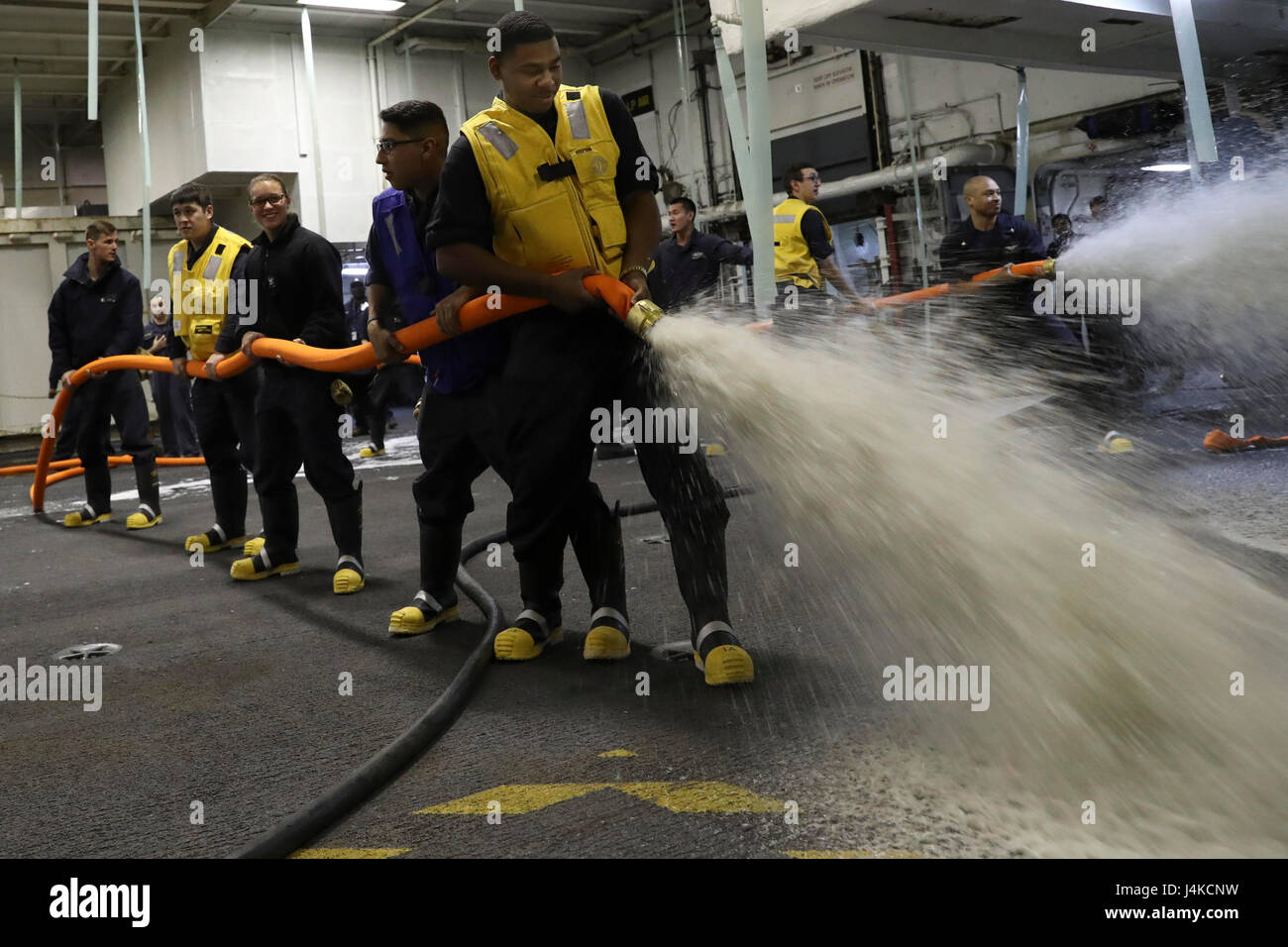 170510-N-LJ375-056  ATLANTIC OCEAN (May 9, 2017) Sailors hold hoses containing a aqueous film forming foam (AFFF) during an AFFF test in the hangar bay of Nimitz-class aircraft carrier USS Abraham Lincoln (CVN 72). Abraham Lincoln is underway after successfully completing its mid-life refueling and complex overhaul and will spend several days conducting sea trials, a comprehensive test of many of the ship’s key systems and technologies. (U.S. Navy photo by Mass Communication Specialist 3rd Class Jacques-Laurent Jean-Gilles/Released) Stock Photo