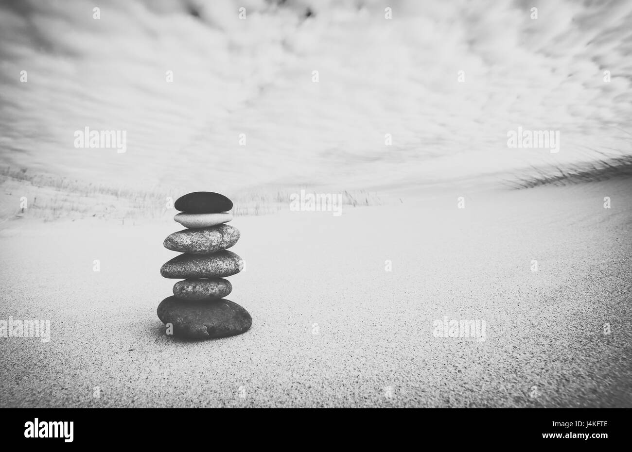 Stack of Balancing Pebbles on Sand Dune, Black and White Edit Stock Photo