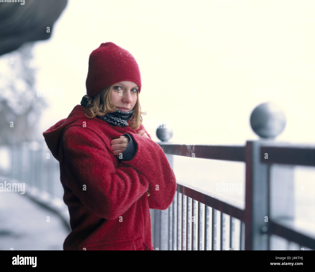 Balustrades, woman, young, winter clothes red, half portrait 20-30 years, Jung-limited, winter casing, casing, cap, headgear, view camera, conception, loneliness, only, cold, freeze, chilly, frosty, uncomfortable, winter walk, winter Stock Photo