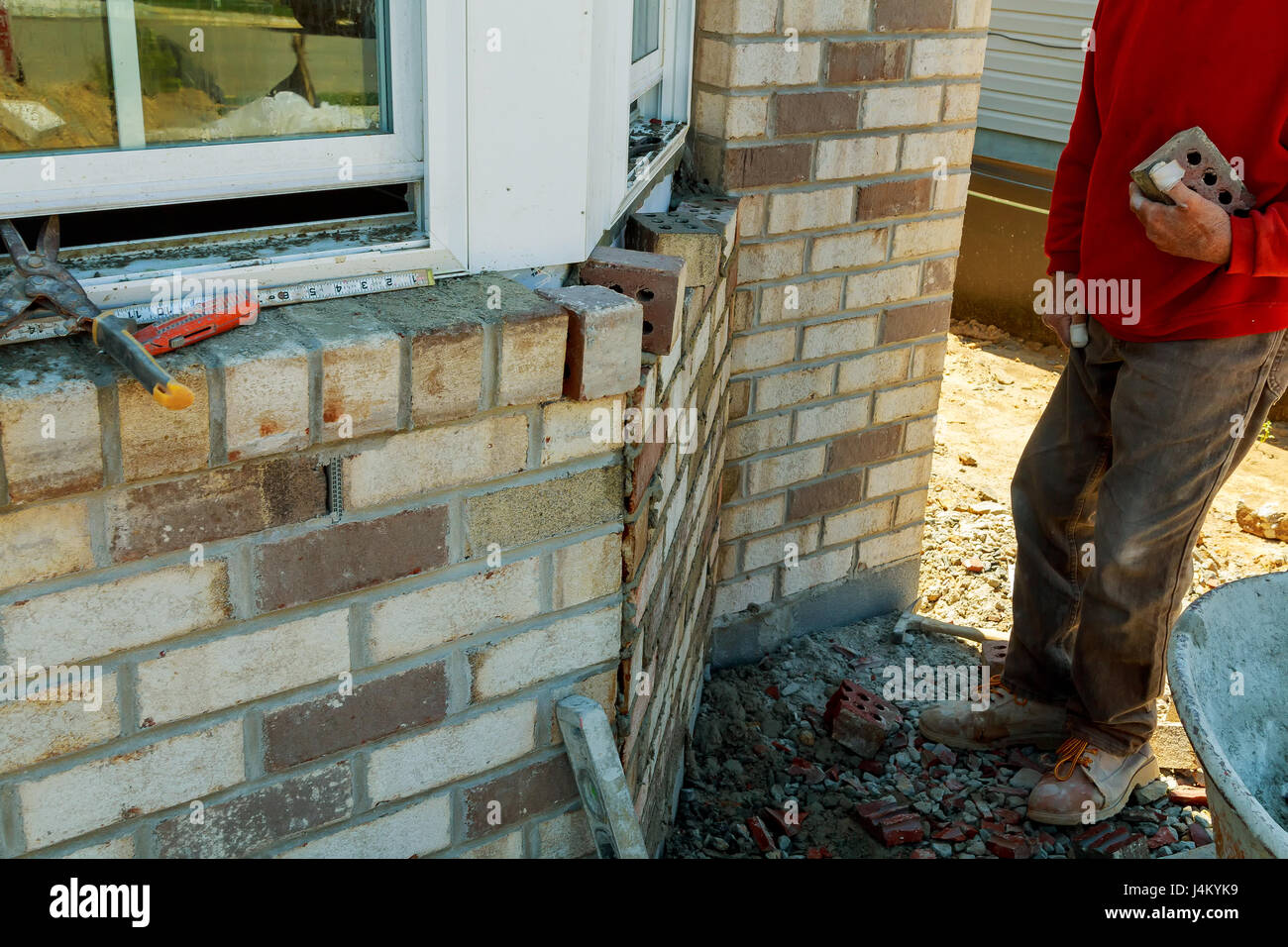 Construction workers laying clay brick to form brick wall at the