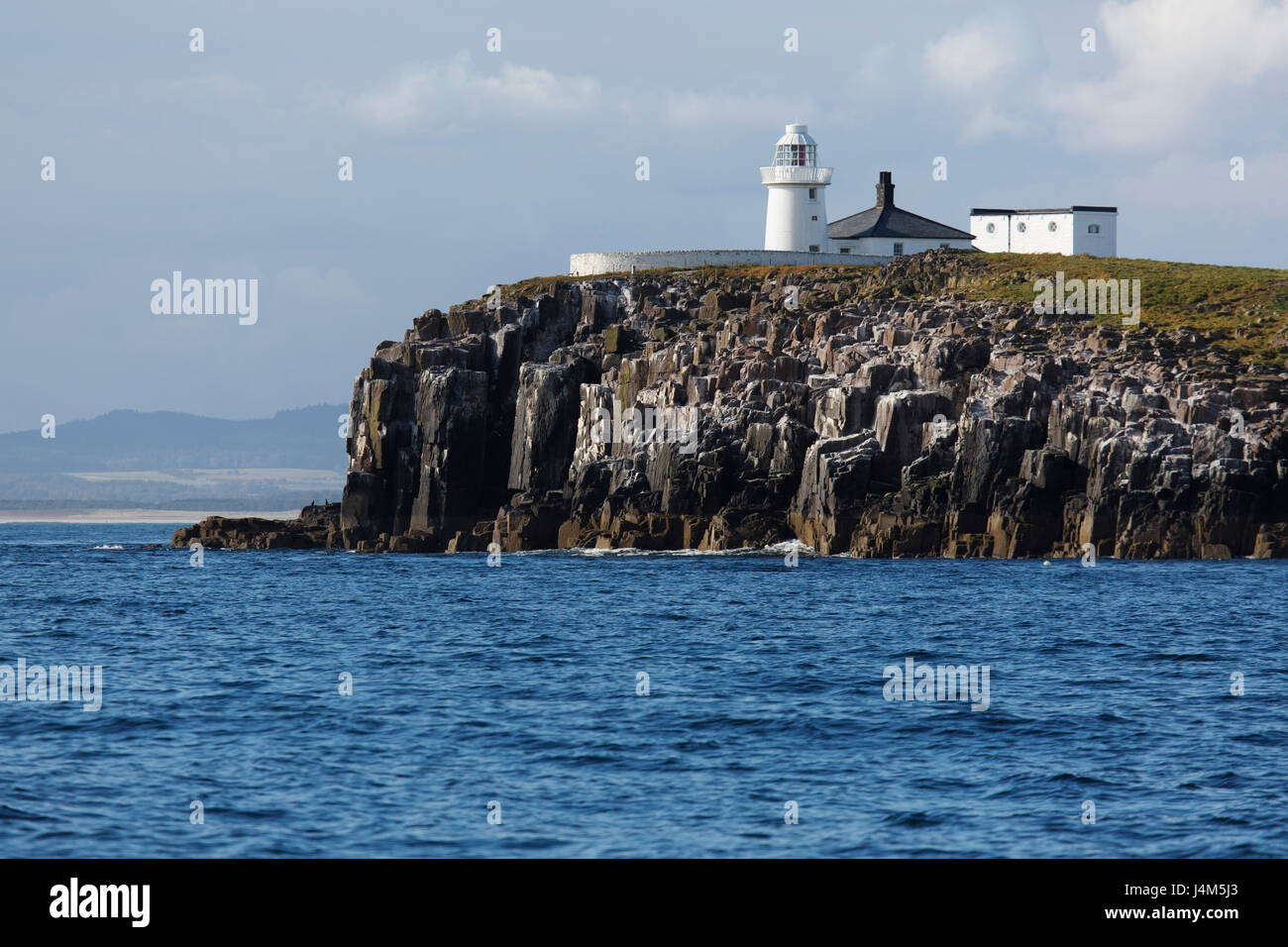 Inner Farne Lighthouse tops the cliff of the Farne Islands off the coast of Northumberland in England. Stock Photo