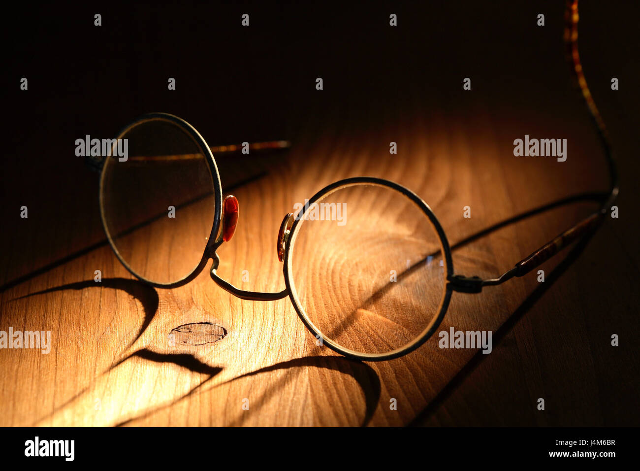 Closeup of old spectacles with long shadow on wooden surface Stock ...