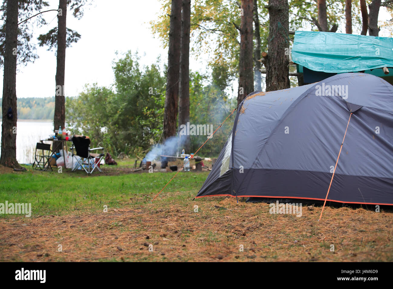 Camping with gray tent in forest near lake Stock Photo - Alamy