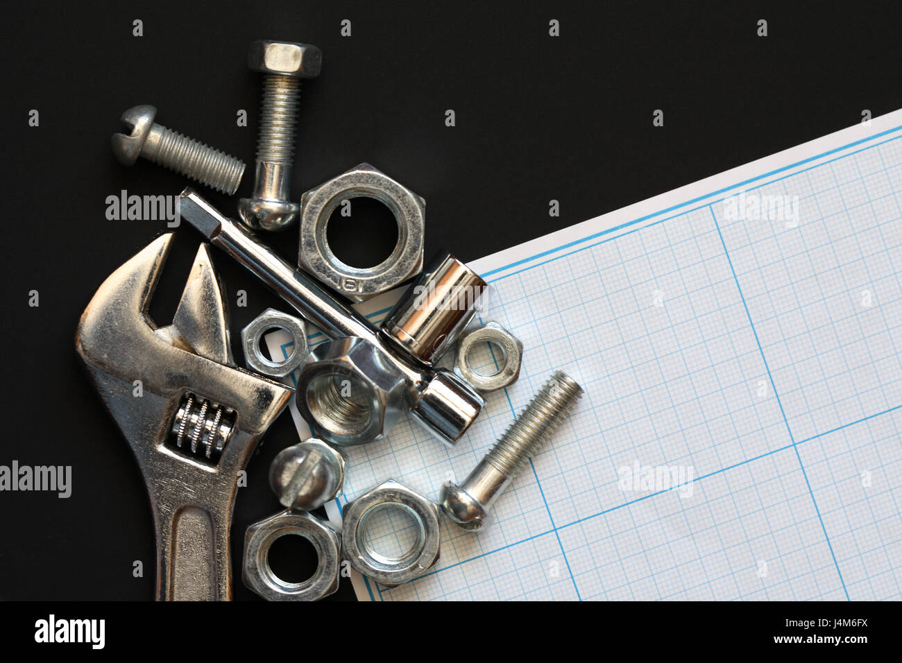 Business concept. Few screw nuts near spanner on graph paper Stock Photo
