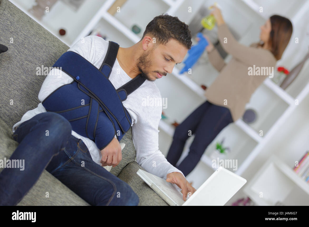 Man with arm in sling using laptop computer Stock Photo - Alamy