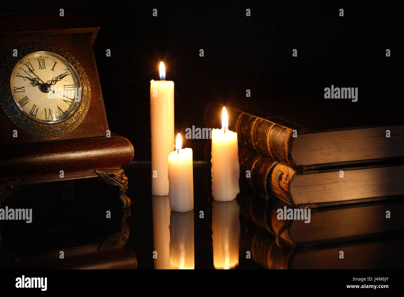 Vintage still life with old books and clock near lighting candles Stock ...