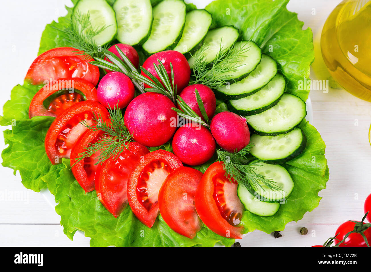 Coarsely chopped fresh cucumber, tomato, radish and lettuce - fresh salad. The concept of healthy eating, diet, vegetarianism Stock Photo