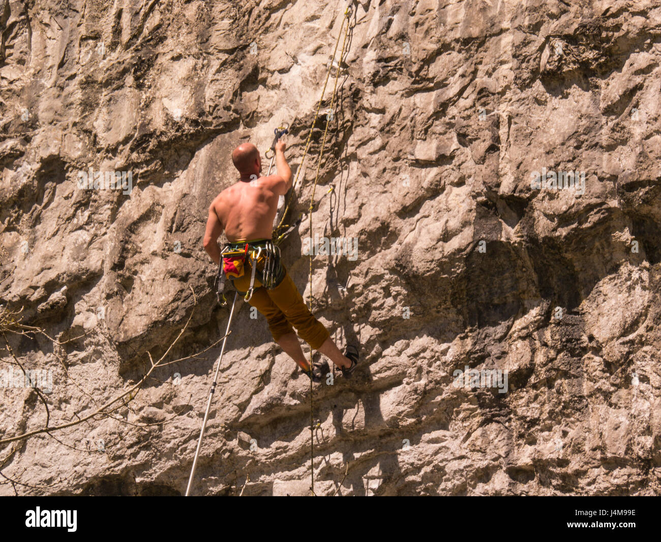 Young bare chested man climbing the limestone escarpment of Malham Cove