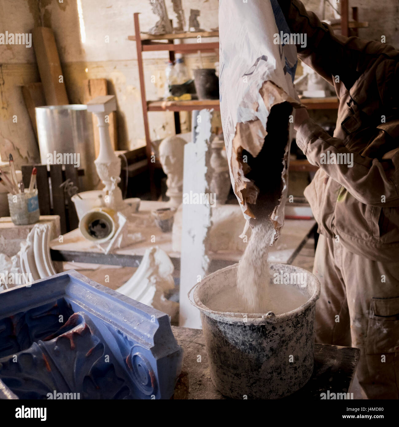 Caucasian artist pouring plaster mix into bucket Stock Photo