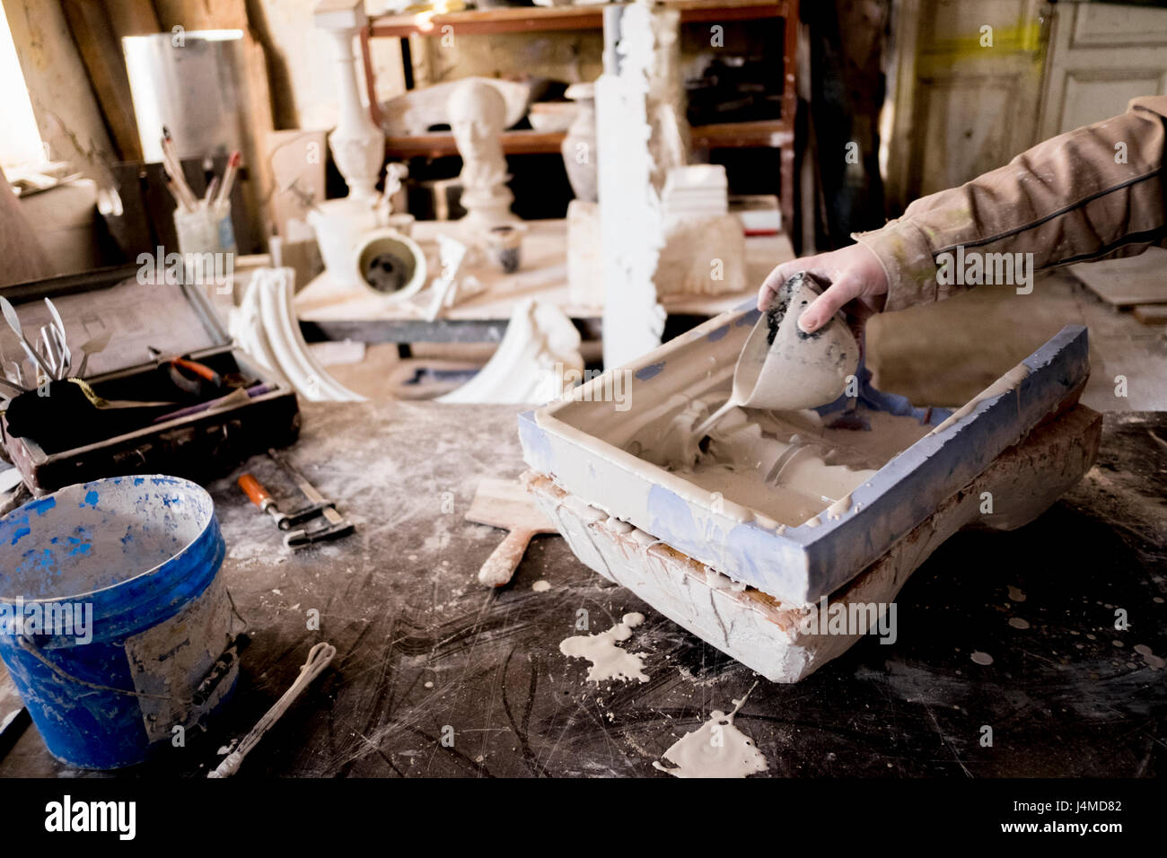 Caucasian artist pouring plaster into mold Stock Photo