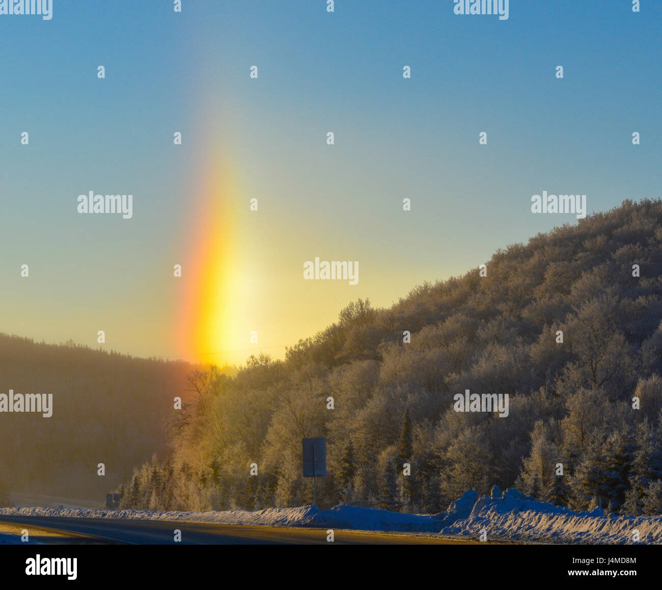 Vertical rainbow touching the road early in the morning during the