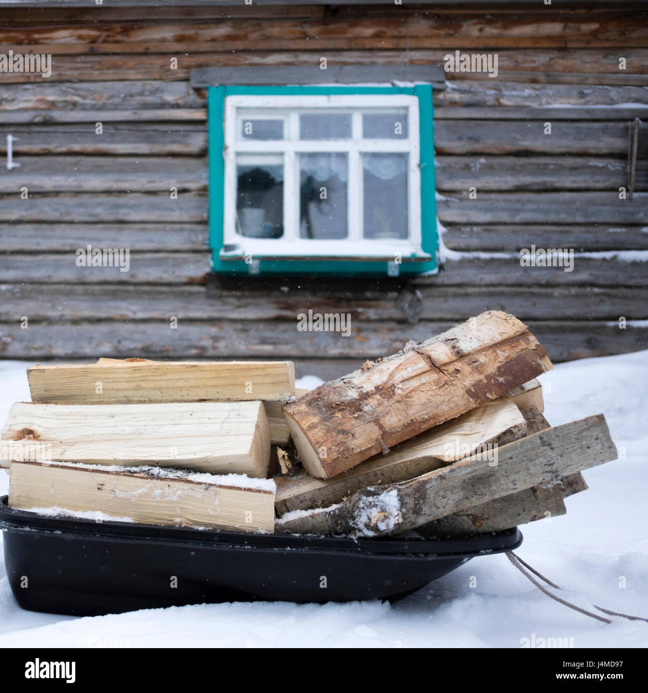 Firewood on sled in snow outside cabin Stock Photo